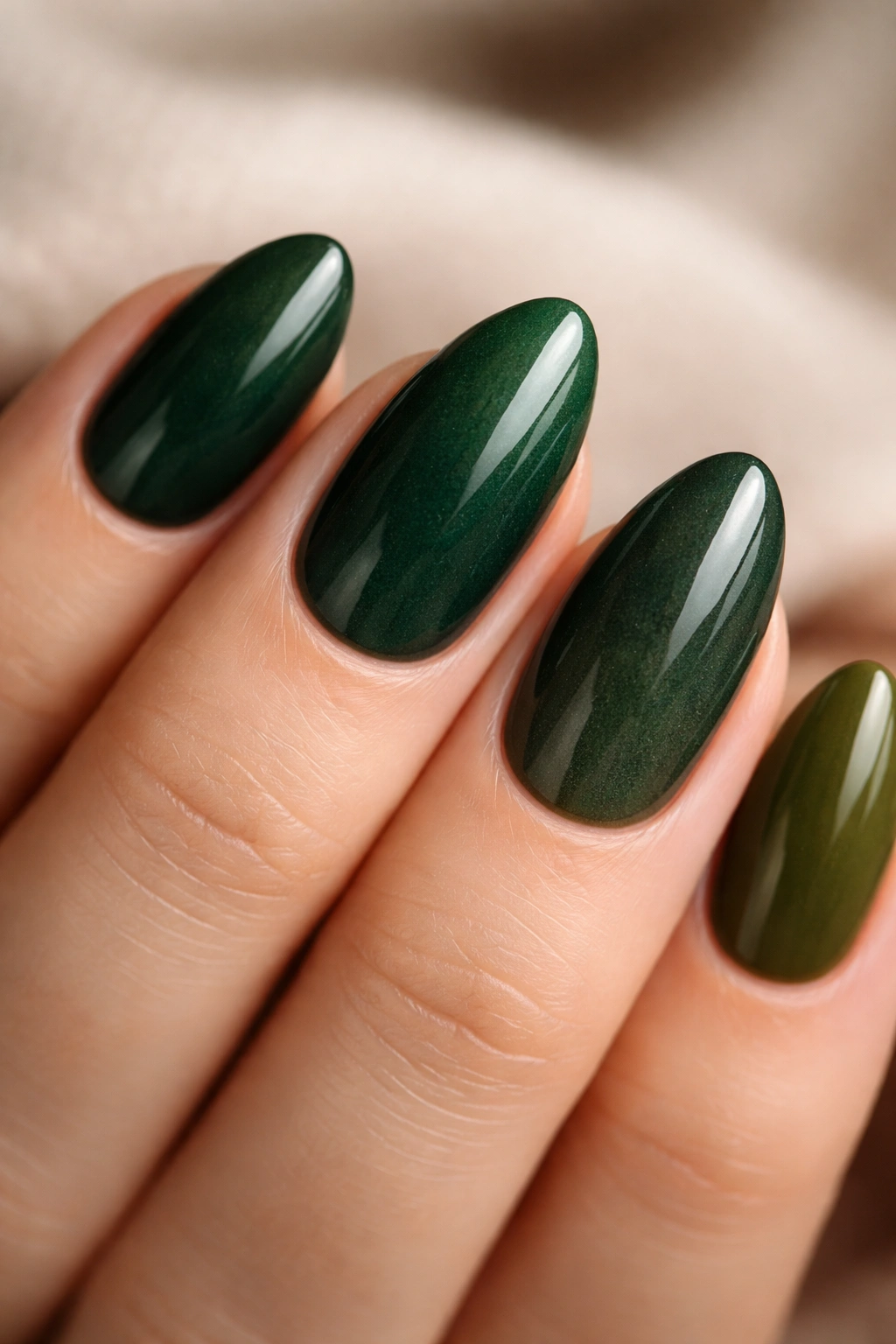 Close-up of a short almond nail with a multi-tone dark green gradient