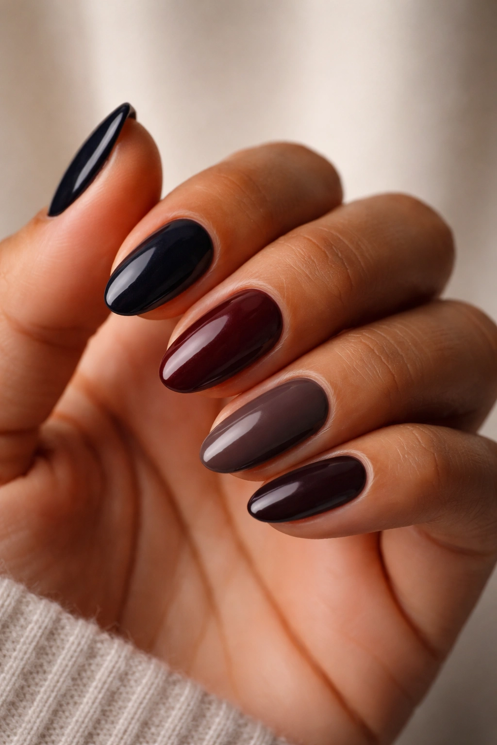 Close-up of a hand with dark nail shades showing flattering tones for various skin undertones
