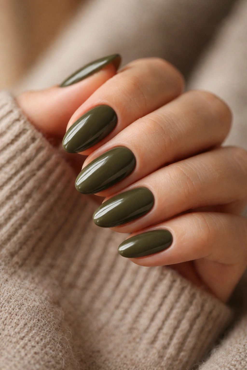 Close-up of short almond nails in dark olive, warm earthy tone.