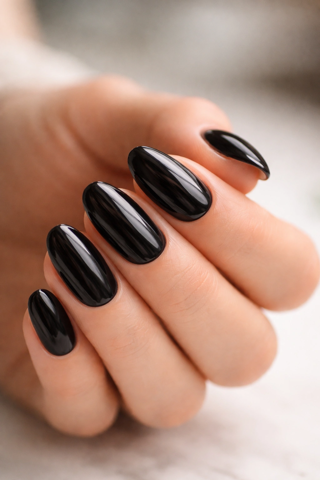 Close-up of short almond nails with glossy dark polish