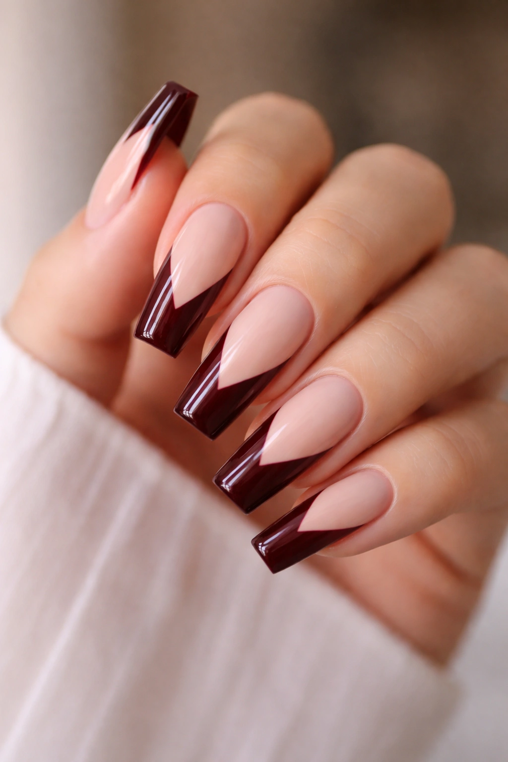 Close-up of coffin nails with dark red tips and geometric negative-space patterns