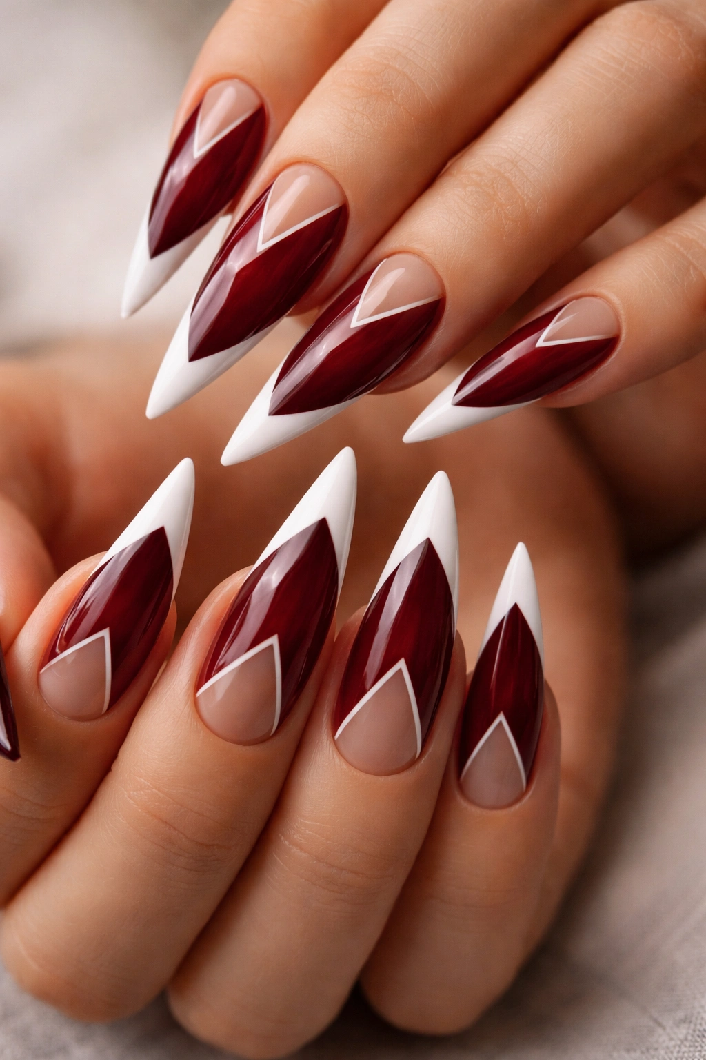Dark red stiletto nails with white tips and geometric negative space