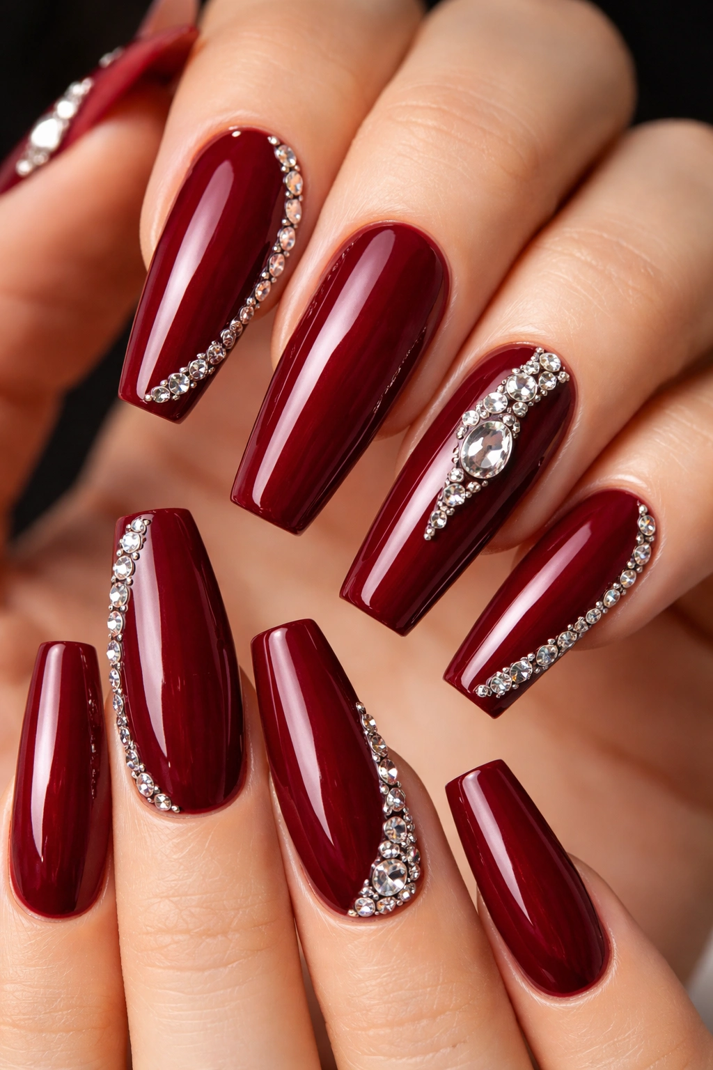 Dark red coffin nails with 3D rhinestone accents along edges.