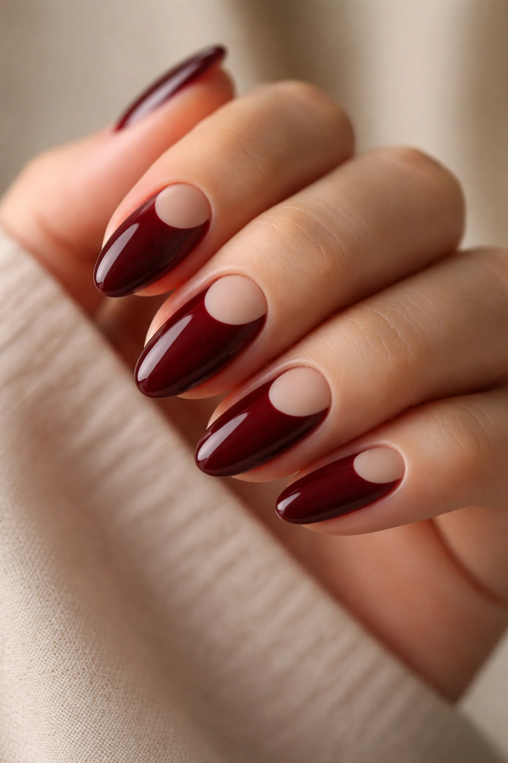 Dark rouge nails with negative-space half-moon design on short almond nails