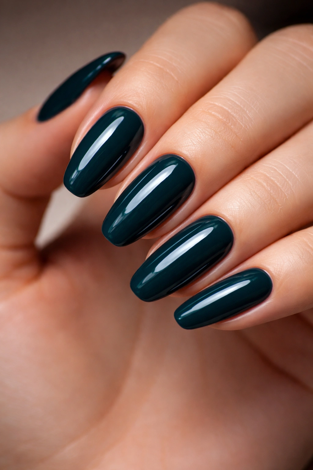 Close-up of dark teal nails with glossy finish on a manicured hand
