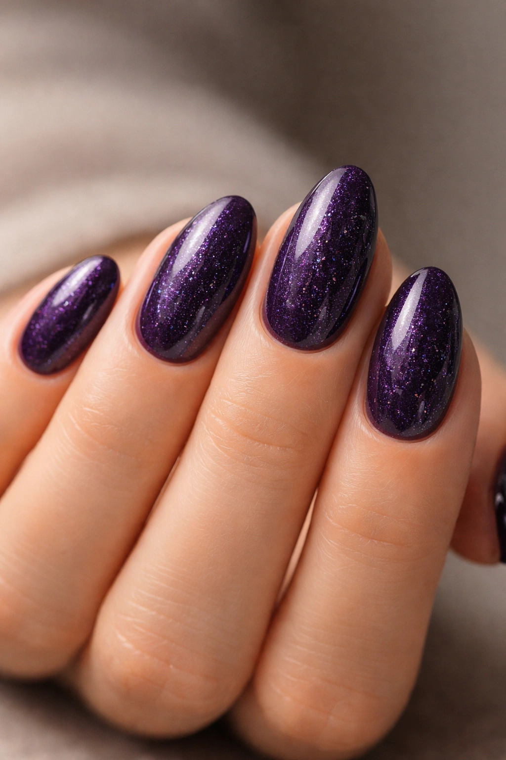 Close-up of Dark Violet micro glitter nails on short almond nails with subtle sparkle