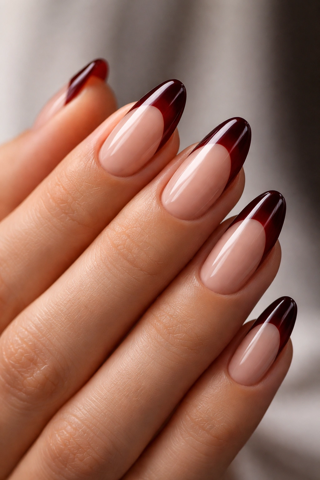 Close-up of nails with dark red French tips on nude base, crisp edge