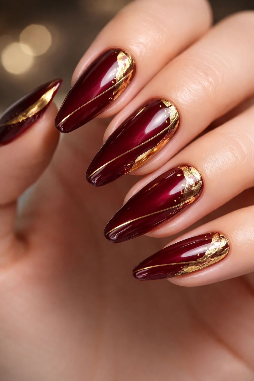 Nails with dark red base and gold accents; luxurious manicure