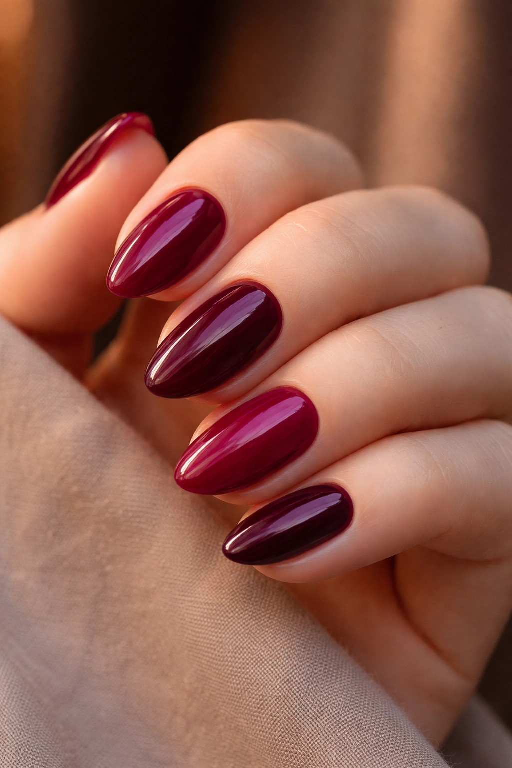 Close-up of deep berry short almond nails in creamy finish.