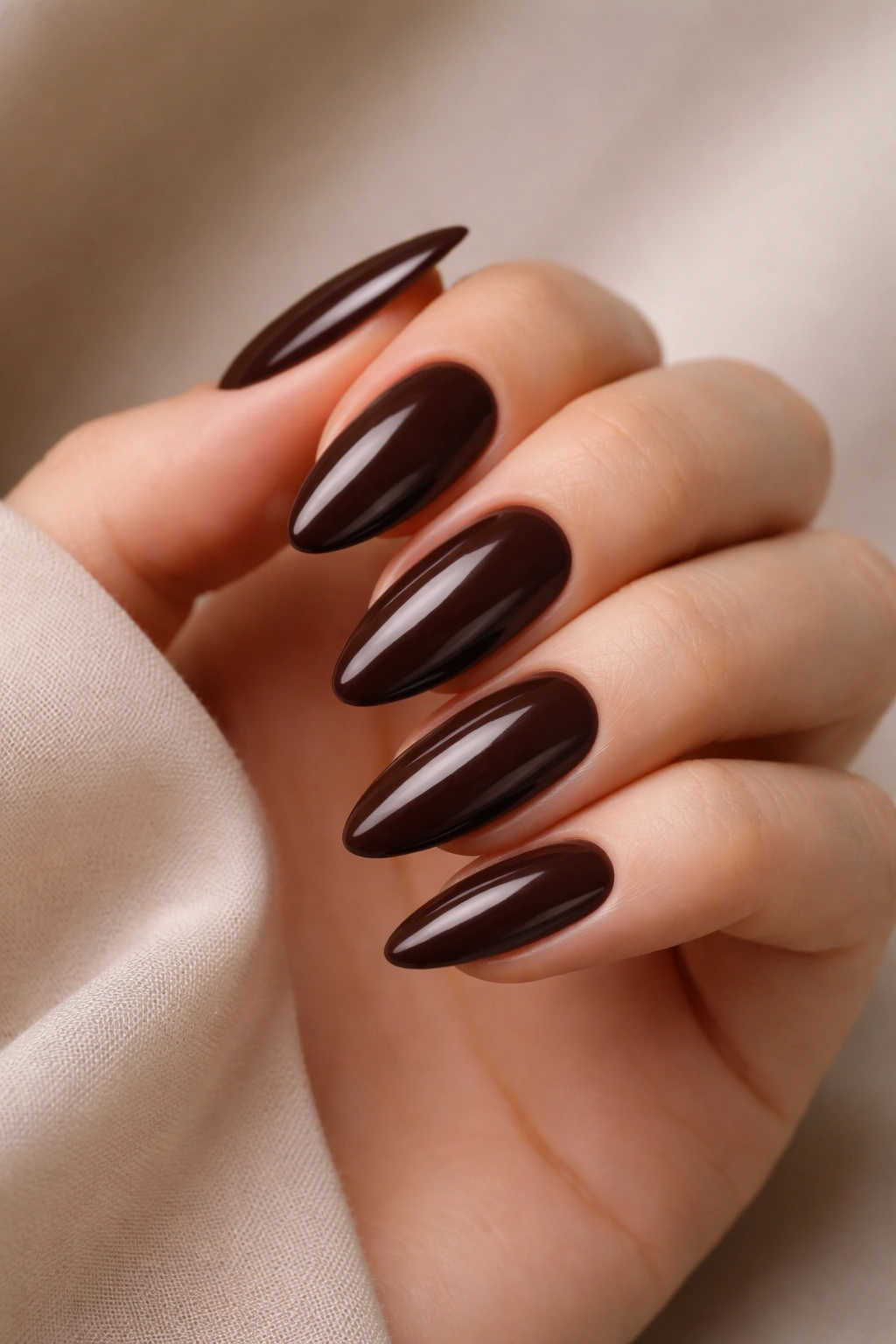 Close-up deep brown almond nails with glossy espresso shade