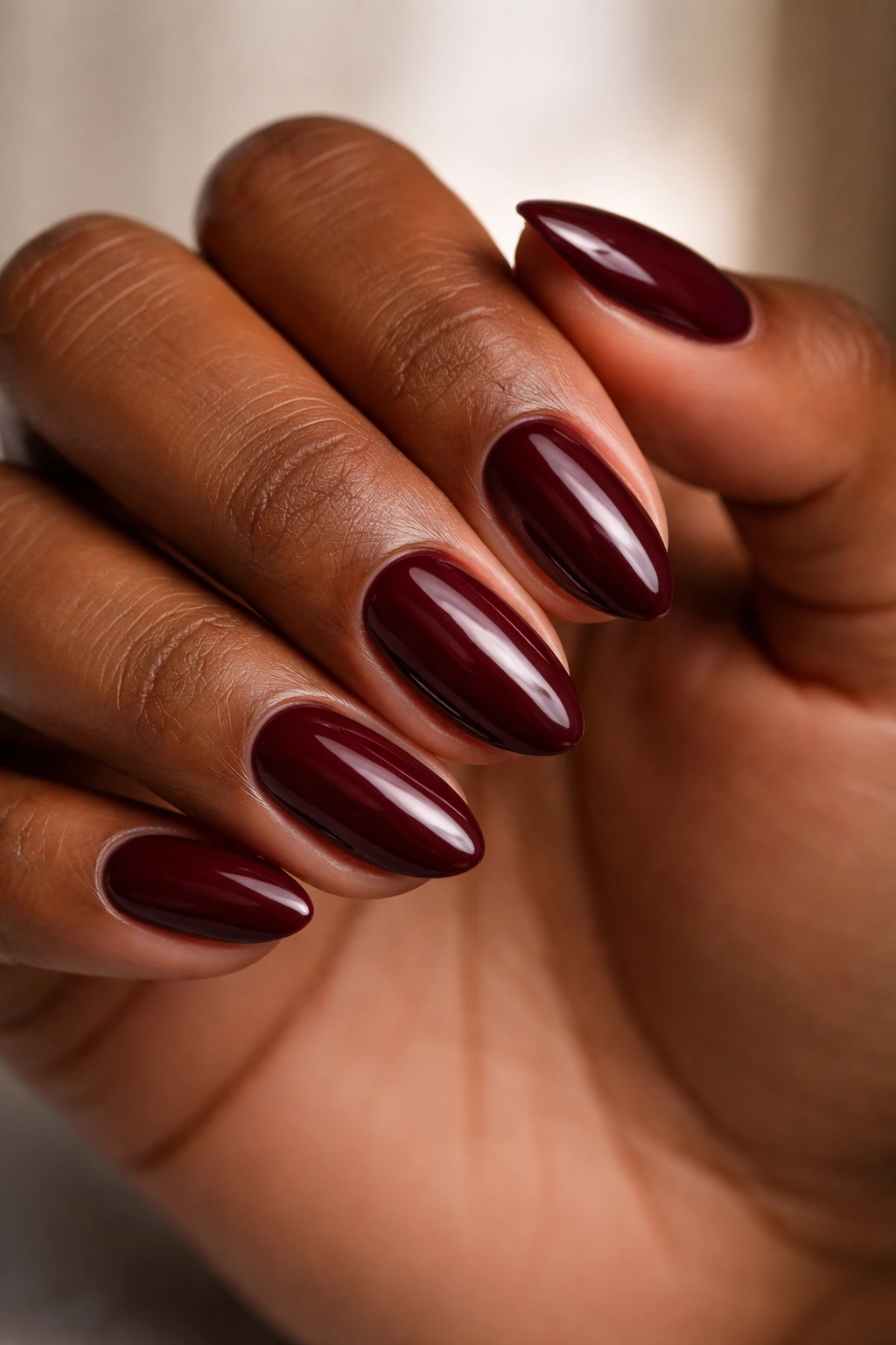 Close-up of deep burgundy short almond nails with glossy finish