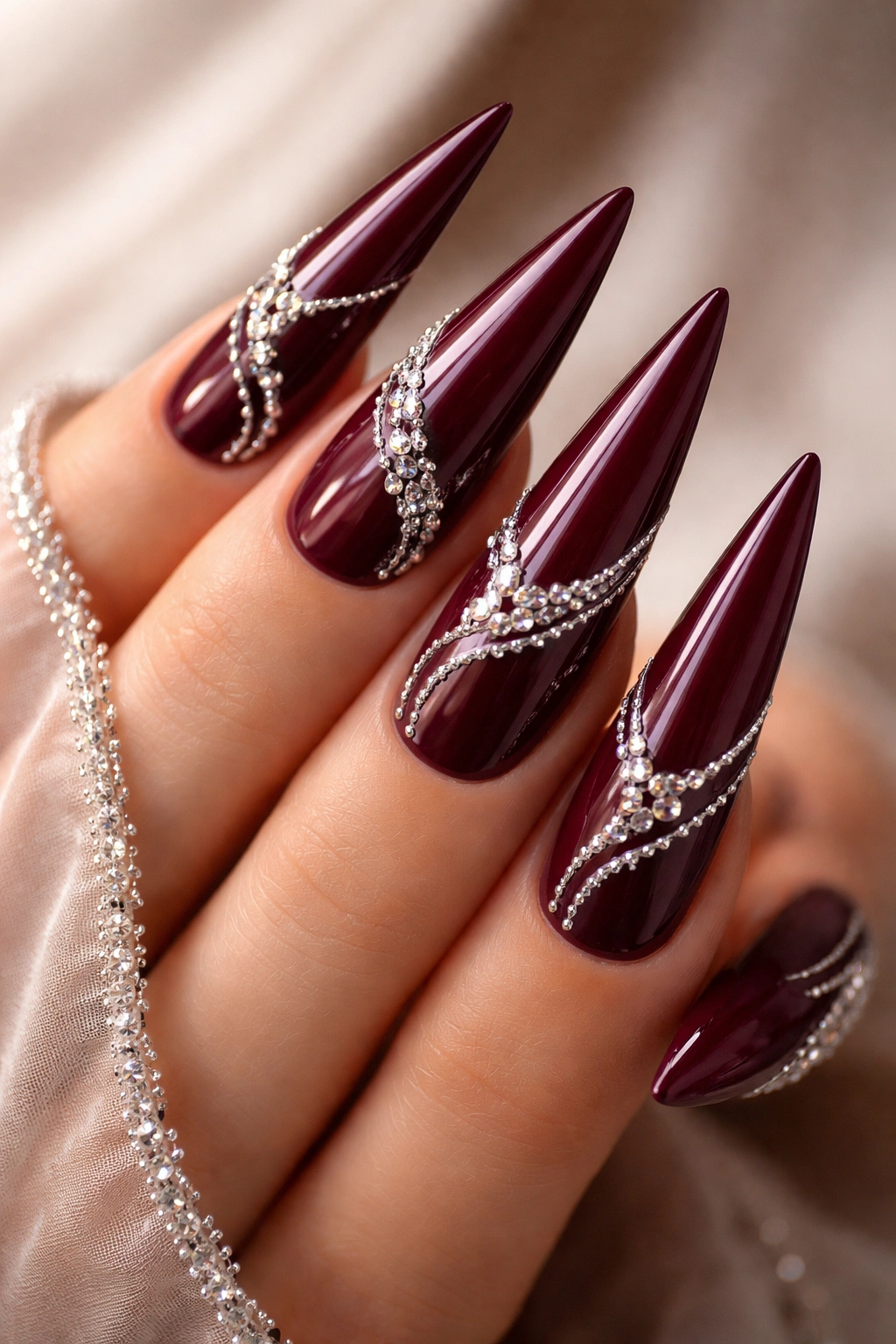 Deep burgundy nails with rhinestone swirl design