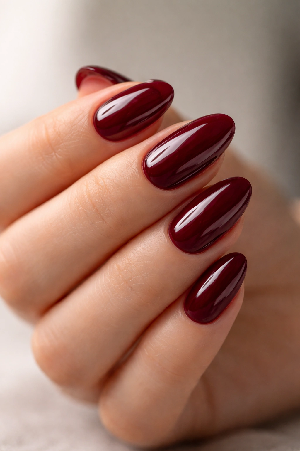 Deep cherry short almond nails with glossy finish.
