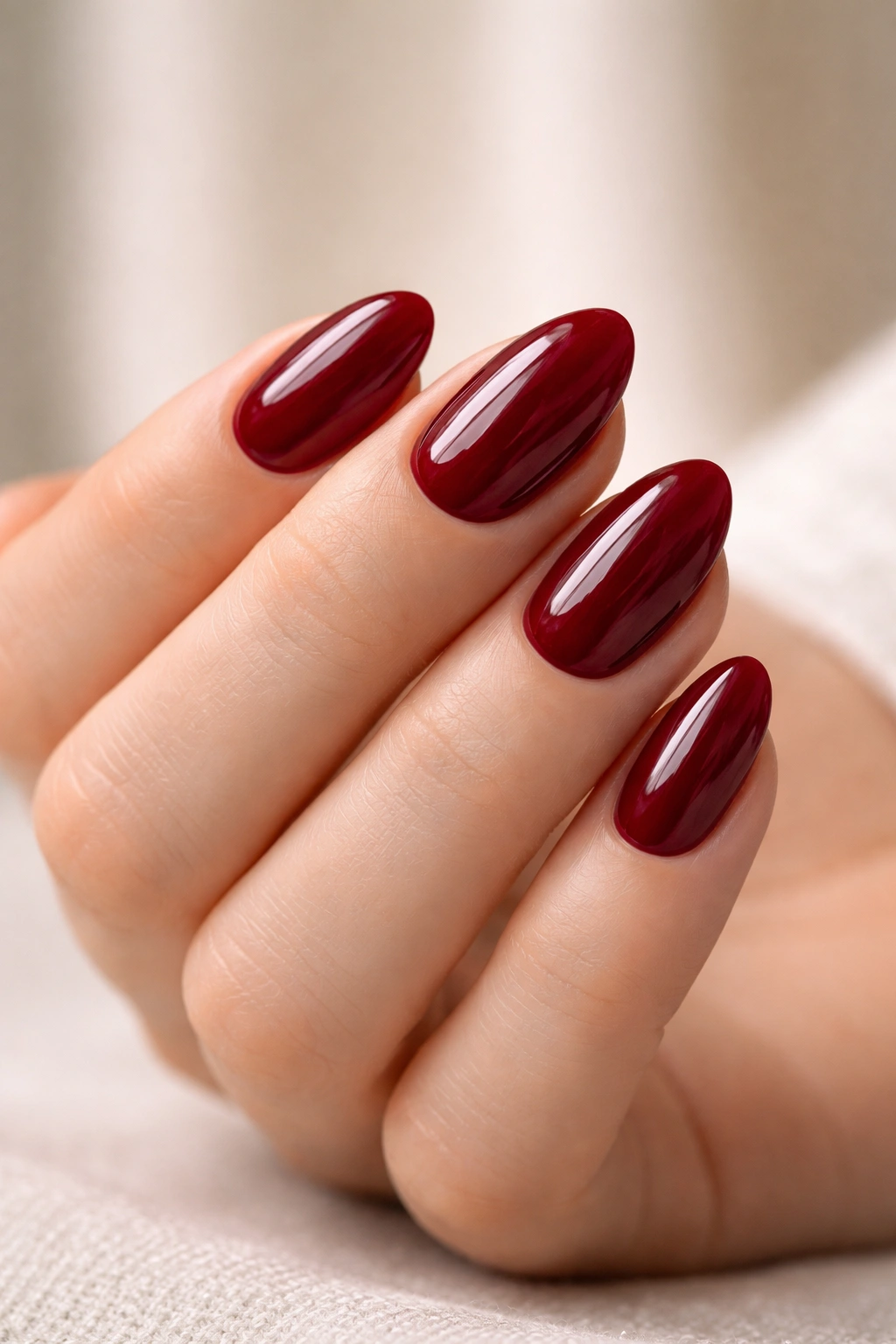 Close-up of deep cherry short almond nails with glossy finish