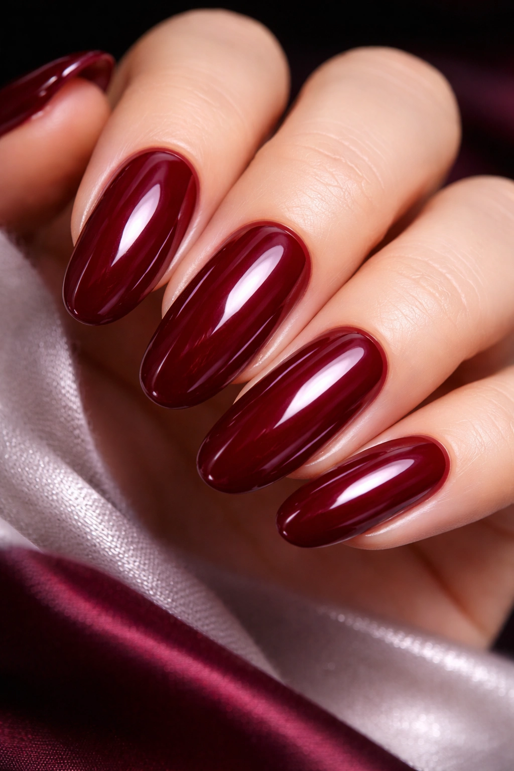 Close-up of long round nails in deep cherry red with a glossy top coat.