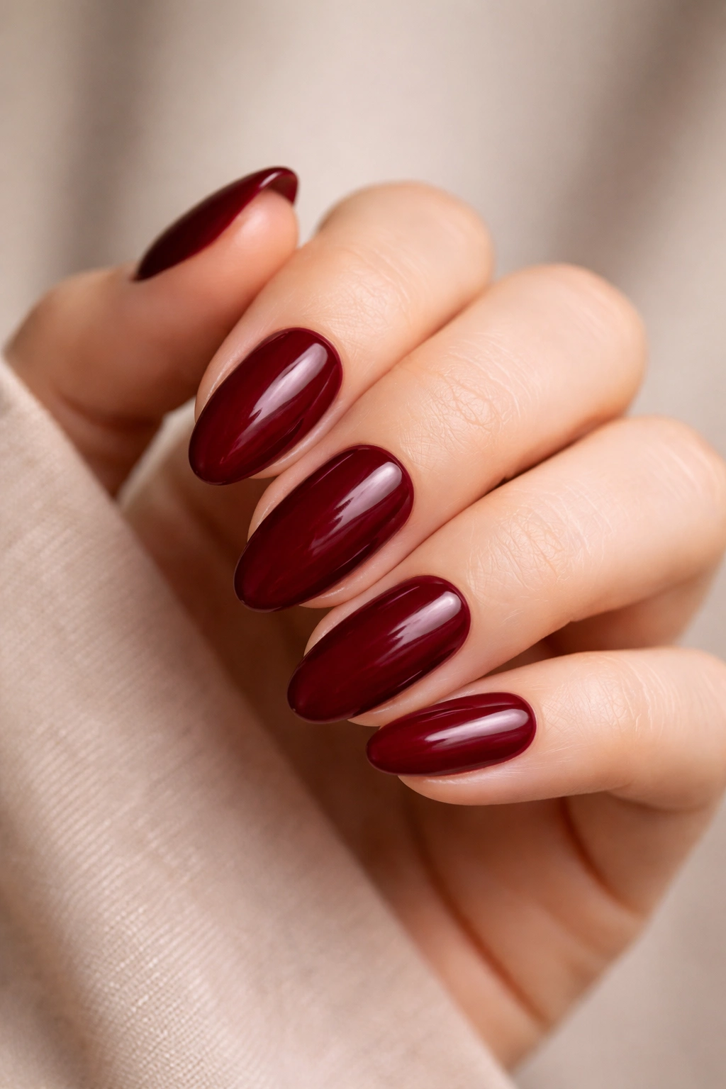 Short almond nails in deep crimson with creamy satin finish