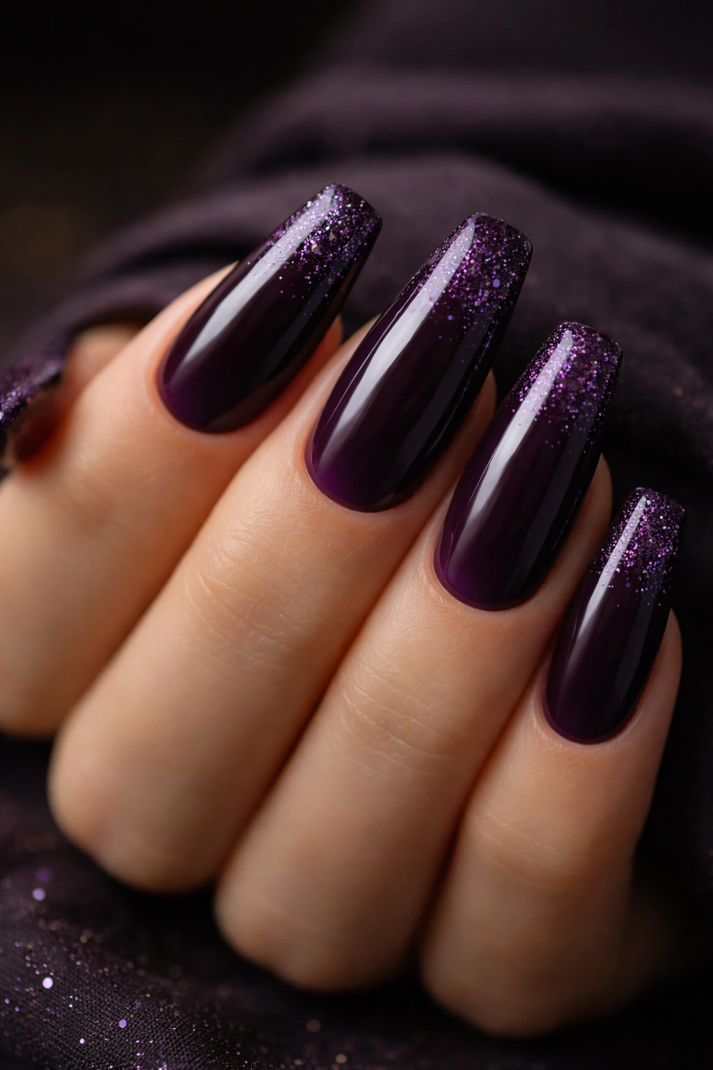 Close-up of coffin nails in deep eggplant with micro glitter scatter.