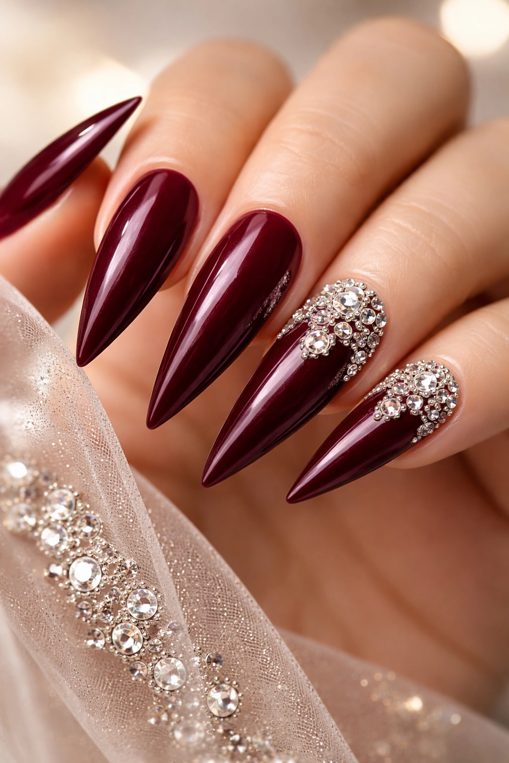 Deep maroon nails with delicate rhinestone accents on accent nails