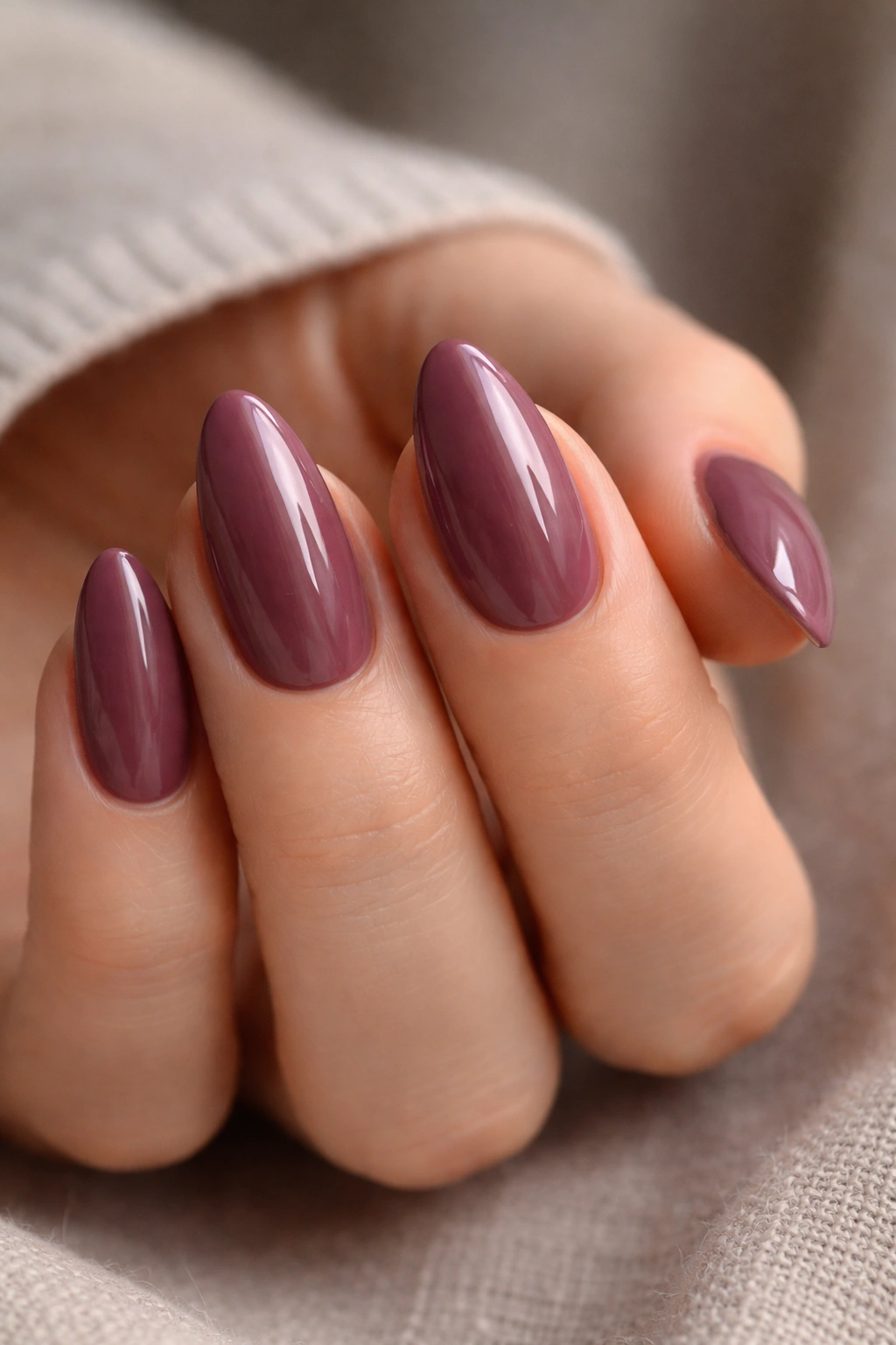 Close-up of short almond nails in deep mauve with a glossy finish