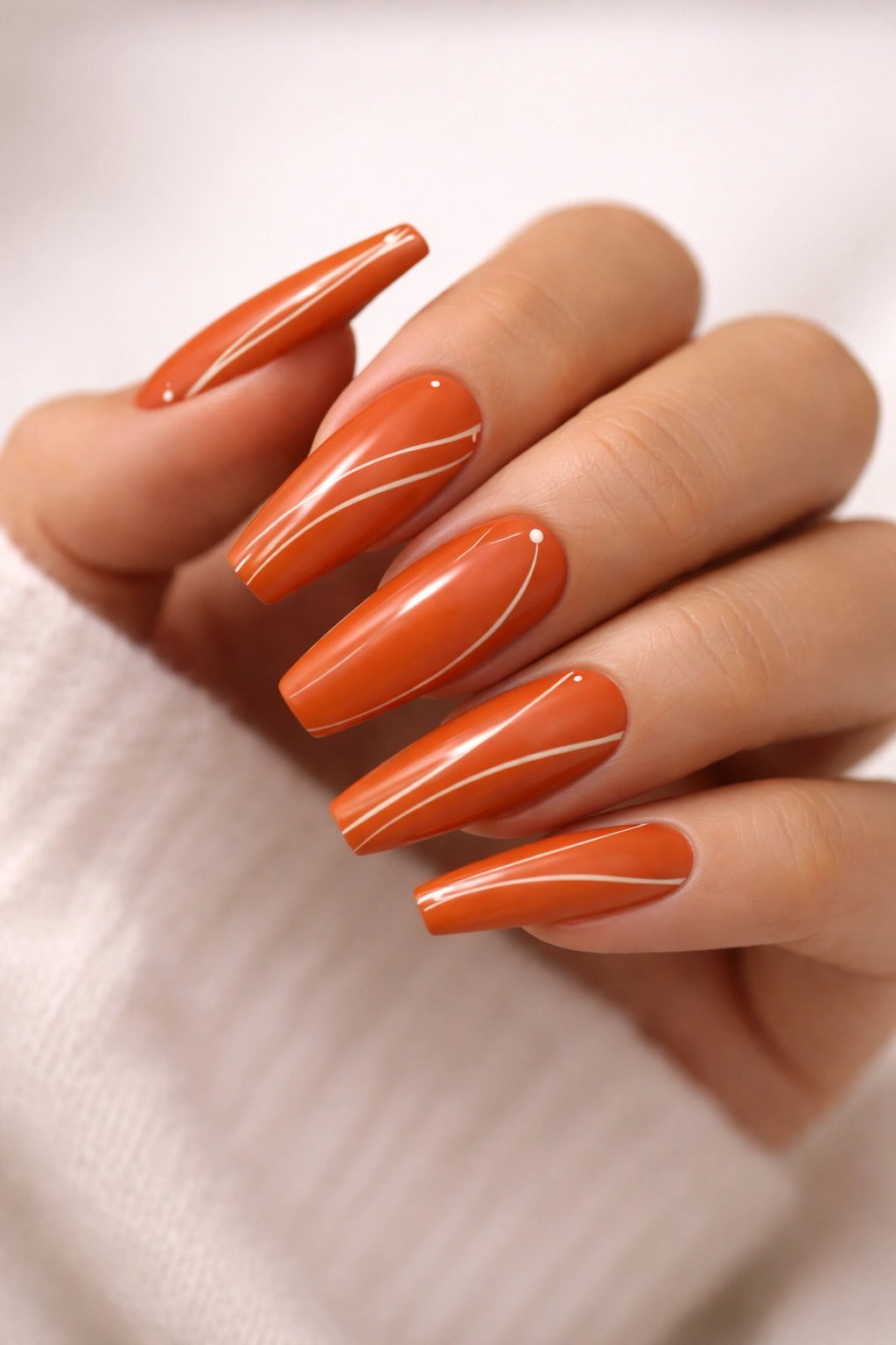Deep orange coffin nails with white minimalist lines and dots