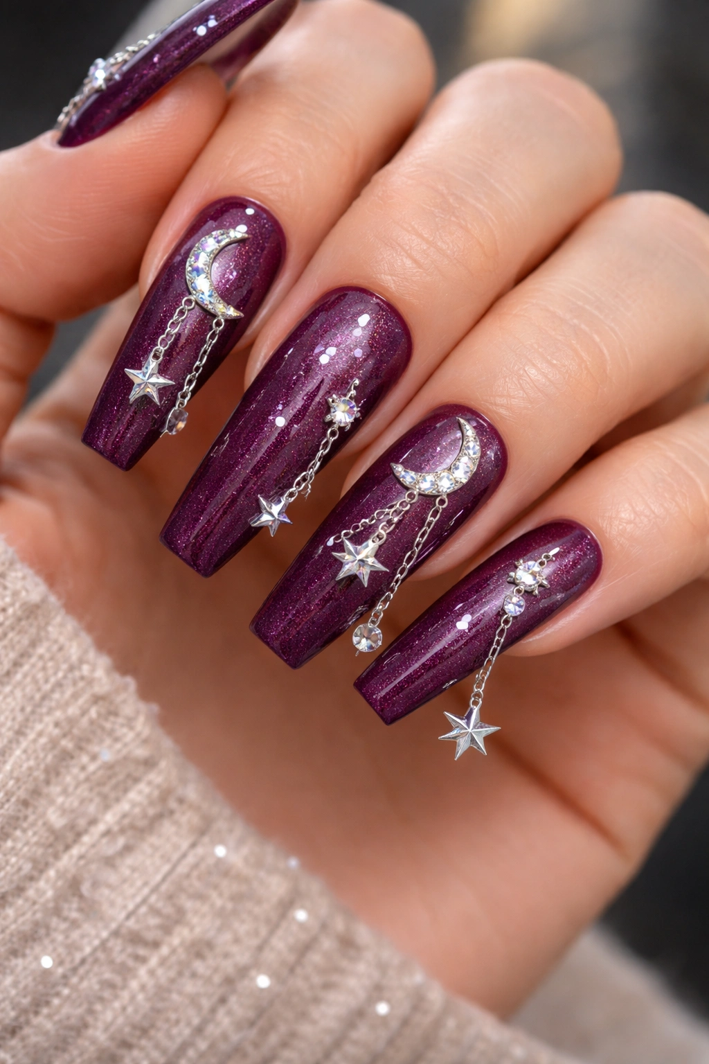 Deep plum nails with silver celestial charms scattered asymmetrically