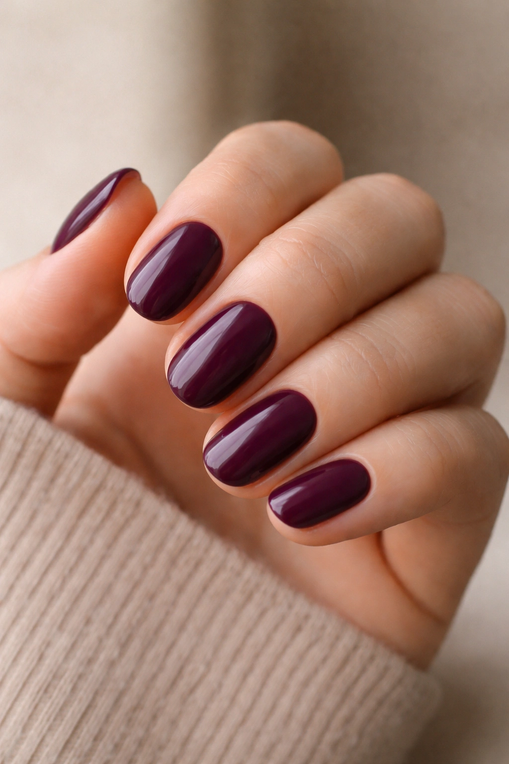 Close-up of deep plum short oval nails with smooth finish