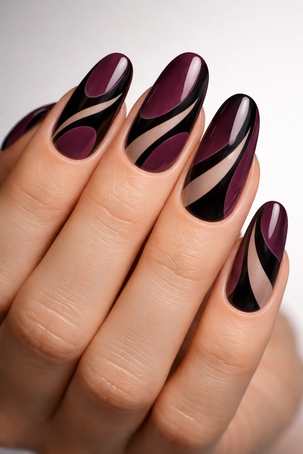 Close-up of deep plum nails with black negative-space design on long round nails