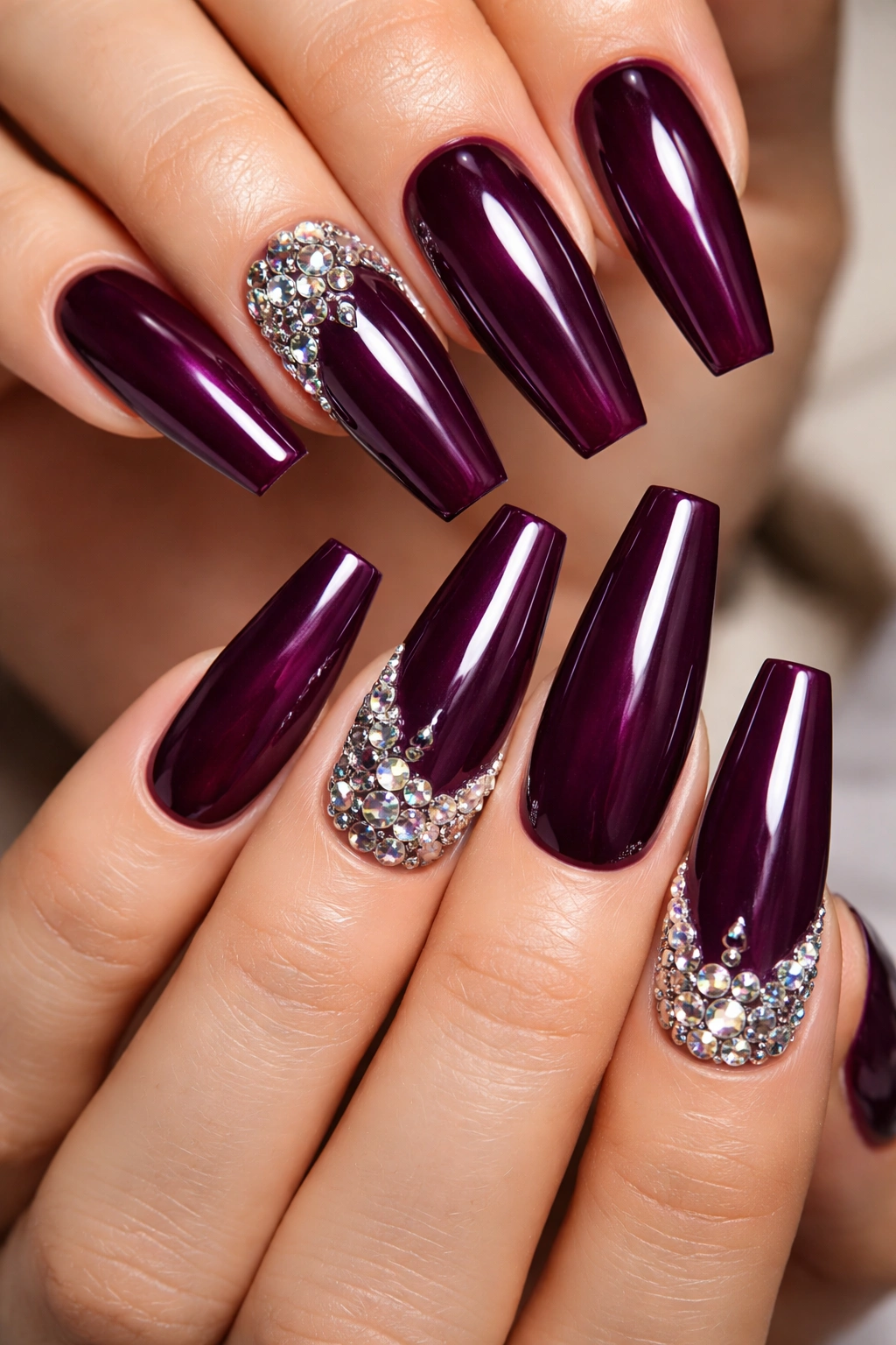 Close-up of deep plum nails with rhinestone accents