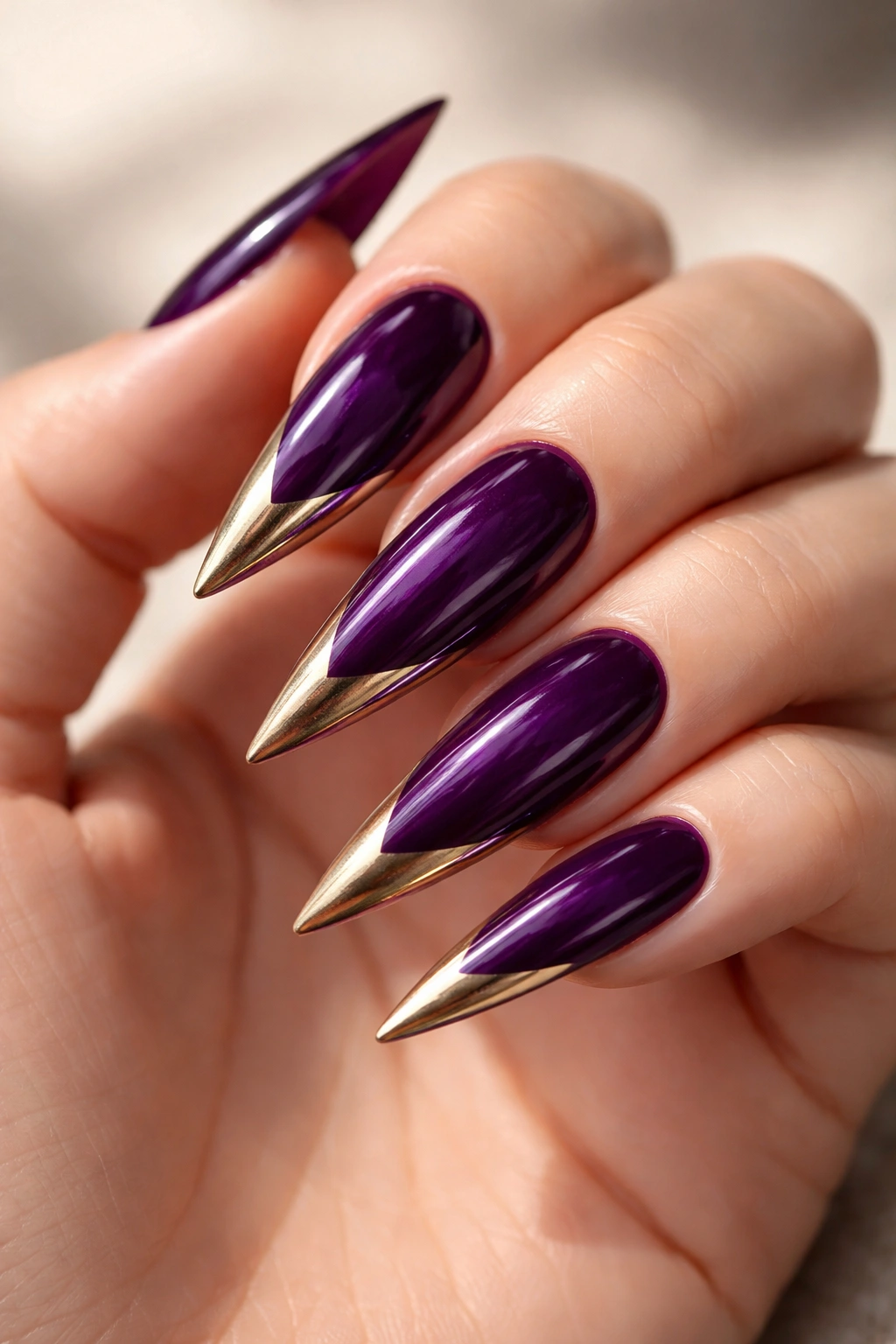 Deep purple stiletto nails with glossy finish and angled metallic French tips