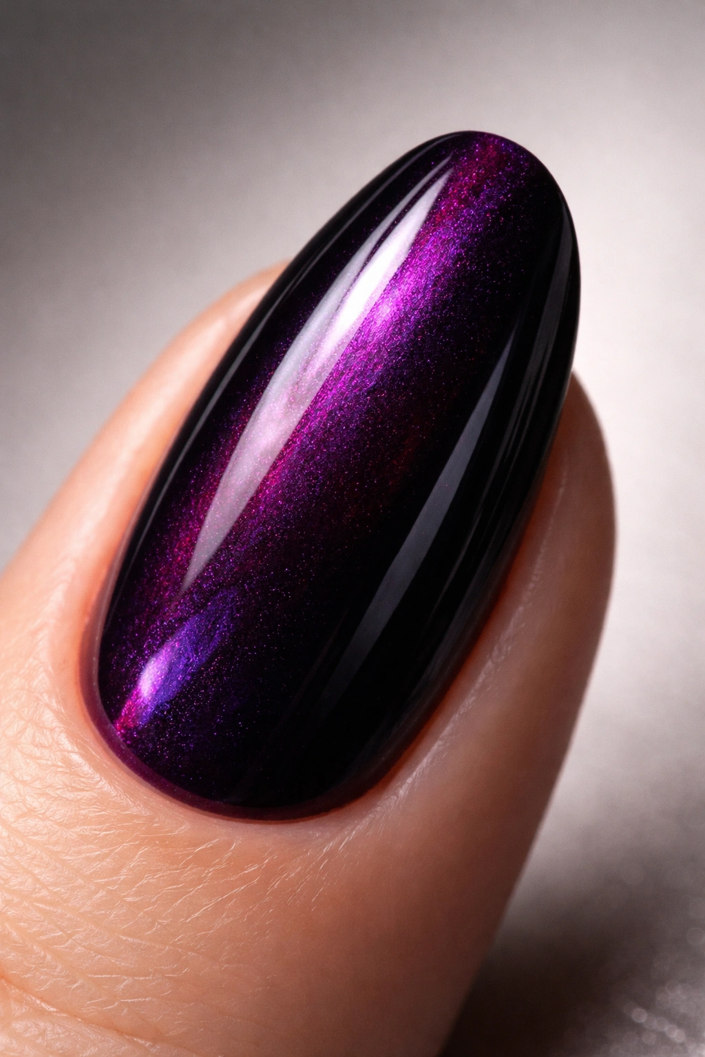 Close-up of a fingernail in deep purple polish showing jewel-toned depth