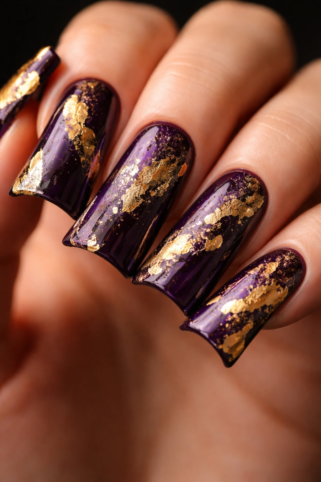 Close-up of deep purple nails with distressed gold foil