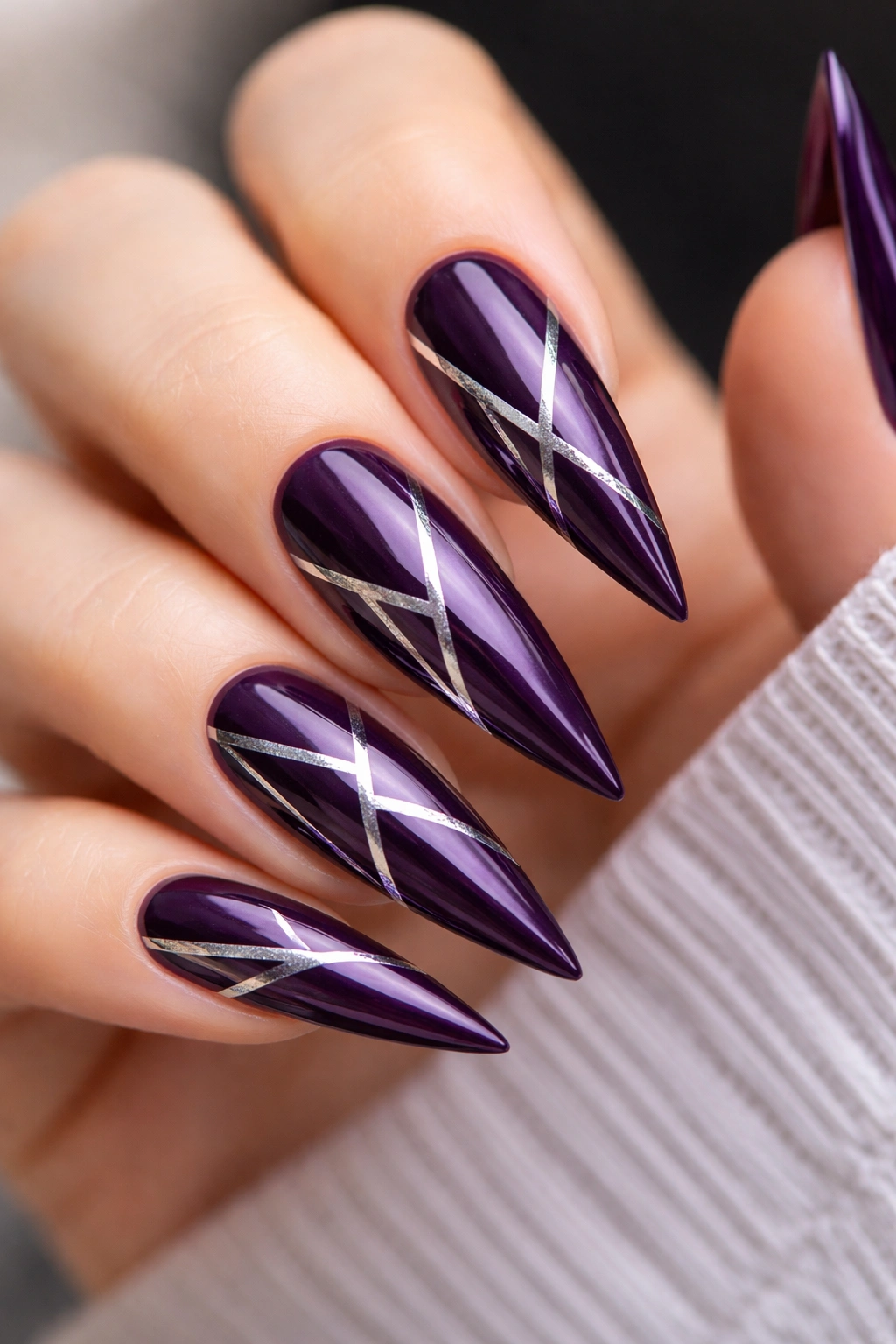 Close-up of deep purple nails with silver geometric accents
