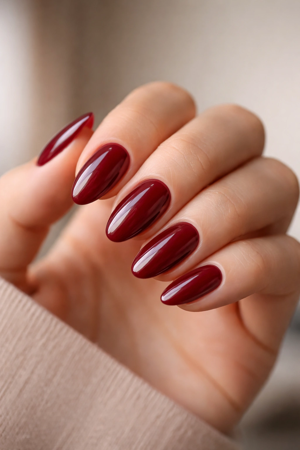 Close-up of deep red short almond nails with glossy finish