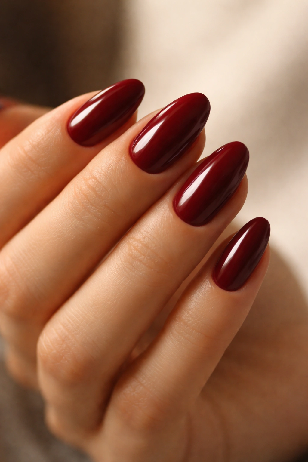 Close-up of short almond nails in deep red polish