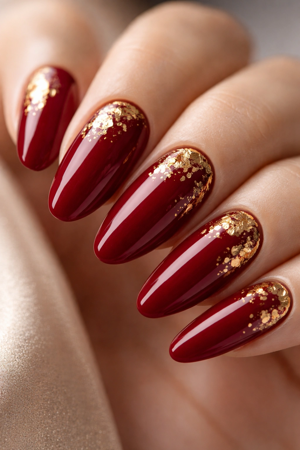 Deep red long oval nails with gold leaf accents