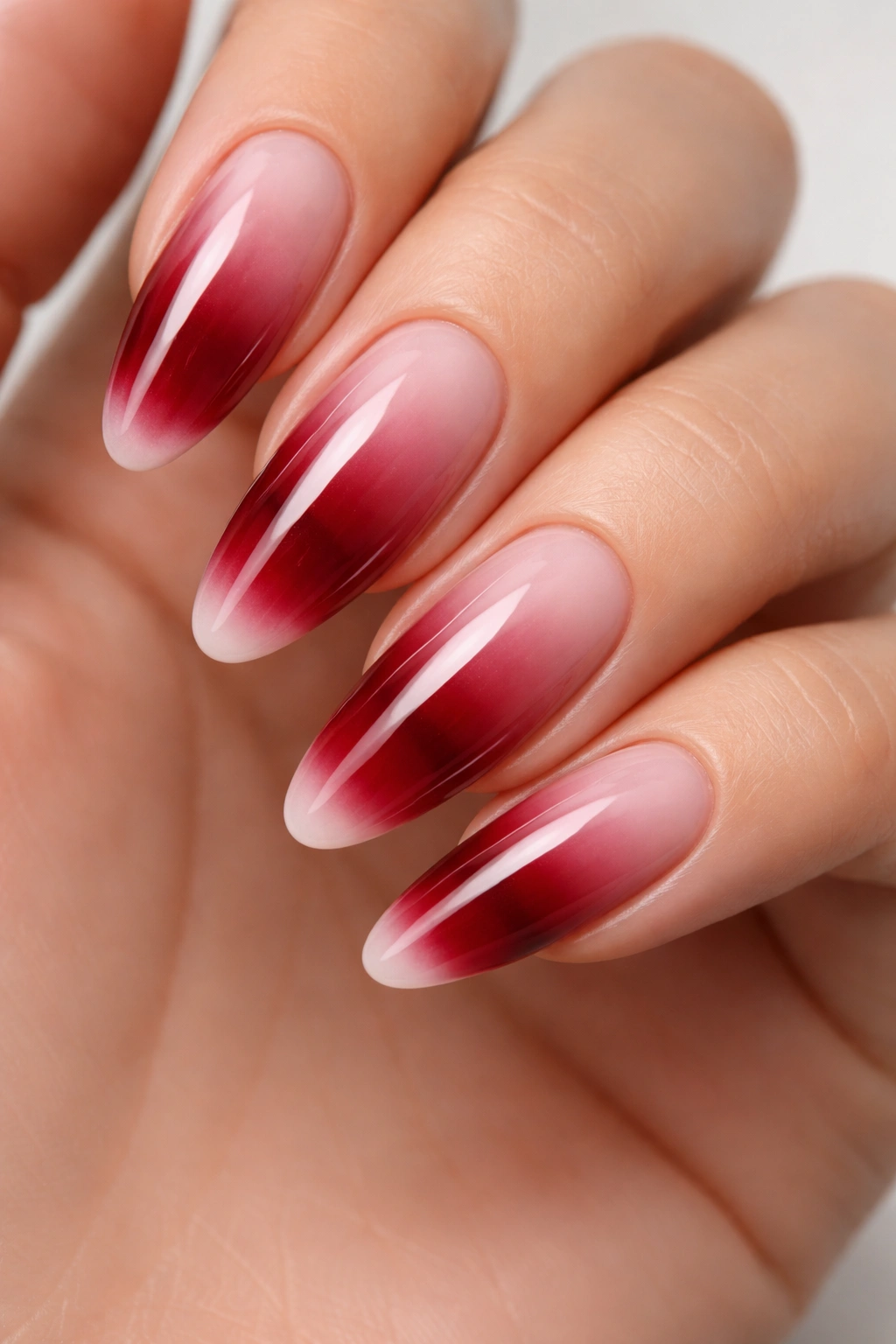 Long round nails with deep red base and extended white gradient tips