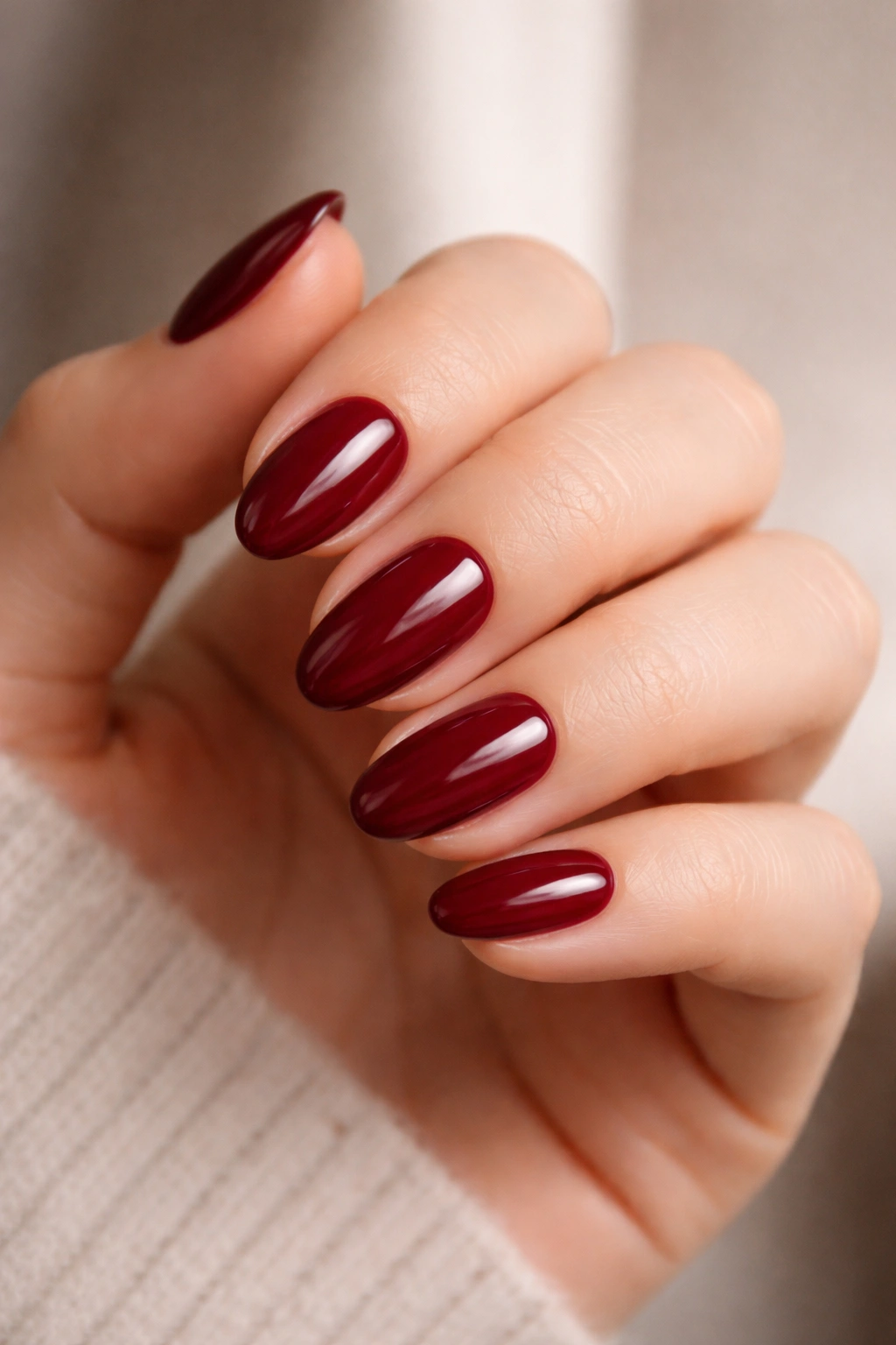 Close-up of deep red almond nails with high-gloss finish on a hand