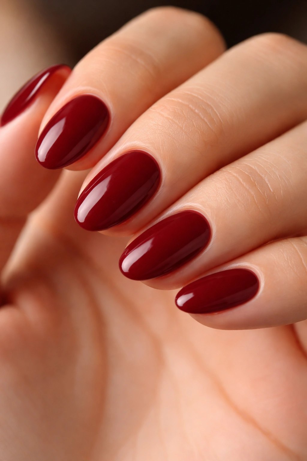Close-up of deep red short almond nails with cream finish and clean edges