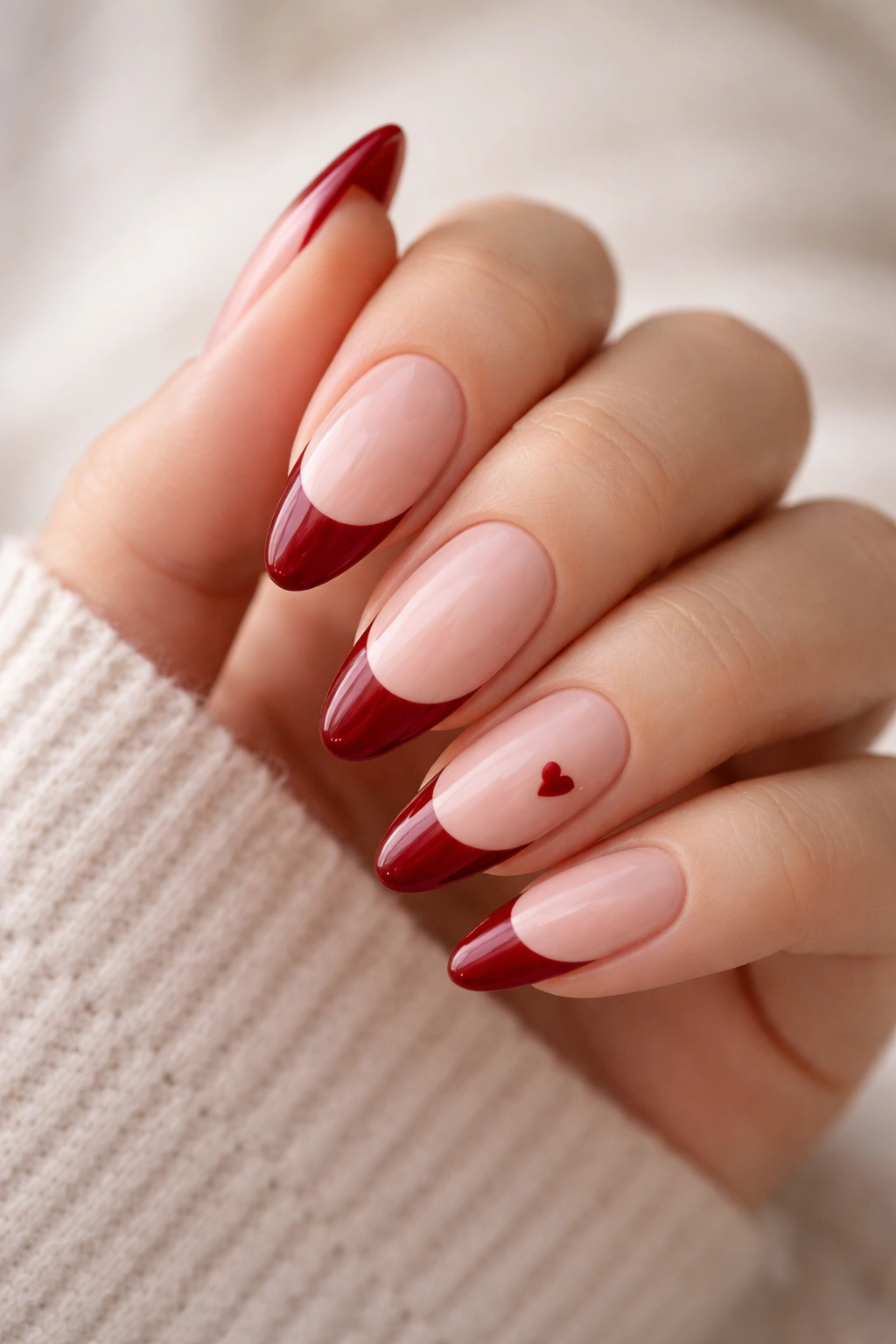 Almond nails with deep red tips and tiny heart accents