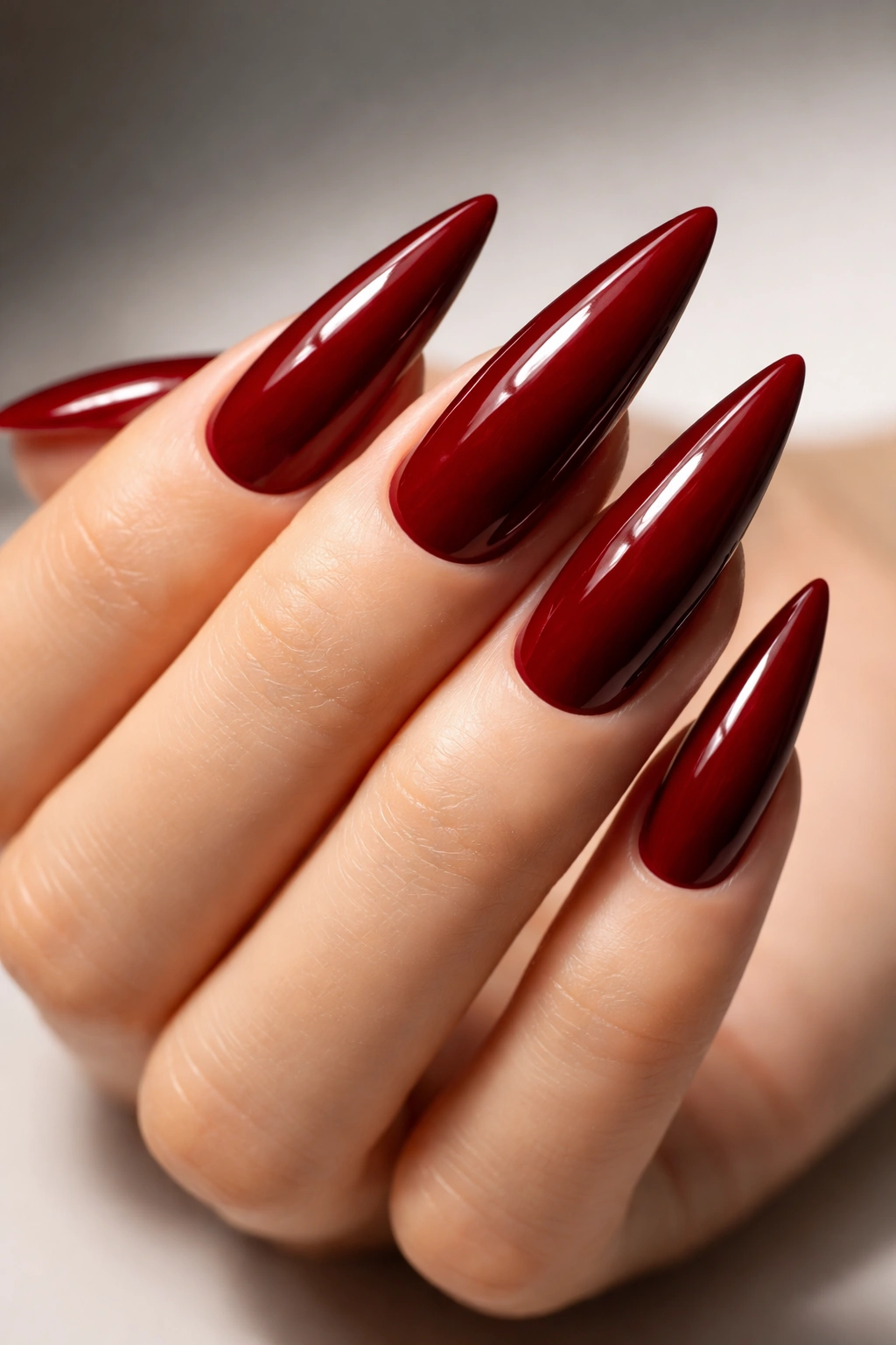 Close-up of deep red stiletto nails with glossy finish