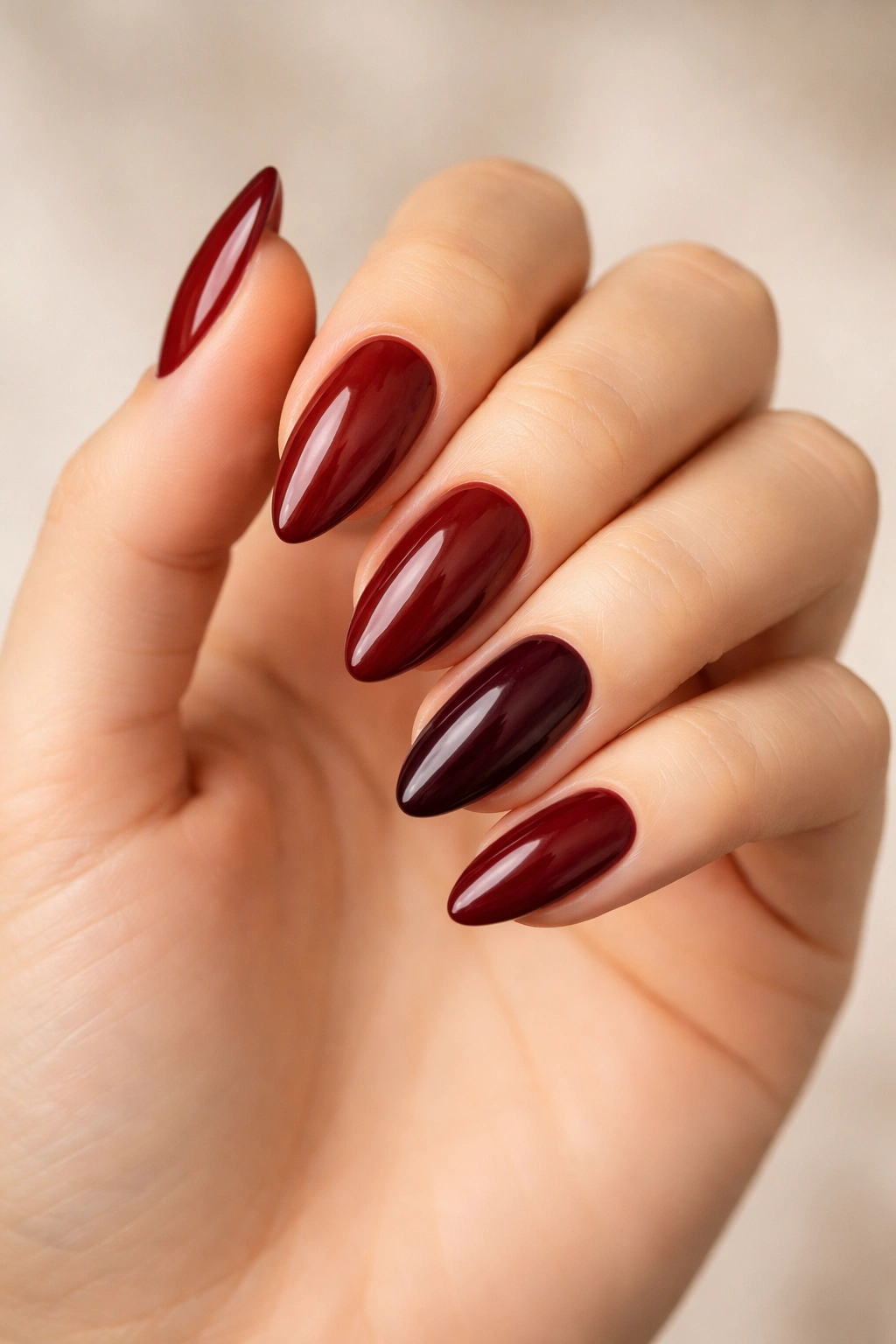Almond nails in a range of deep red shades showing undertone variety