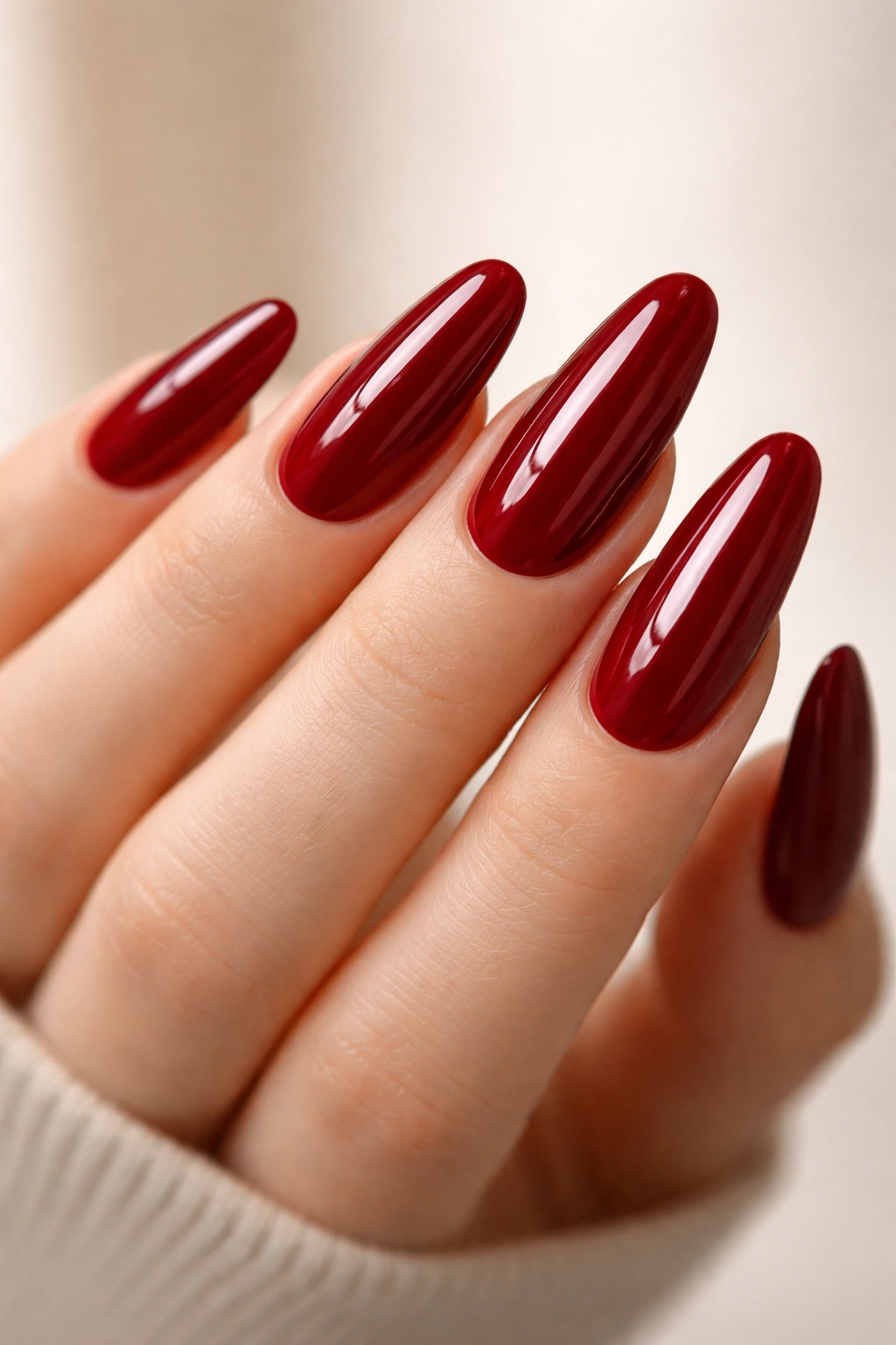 Close-up of deep red glossy oval nails on a hand
