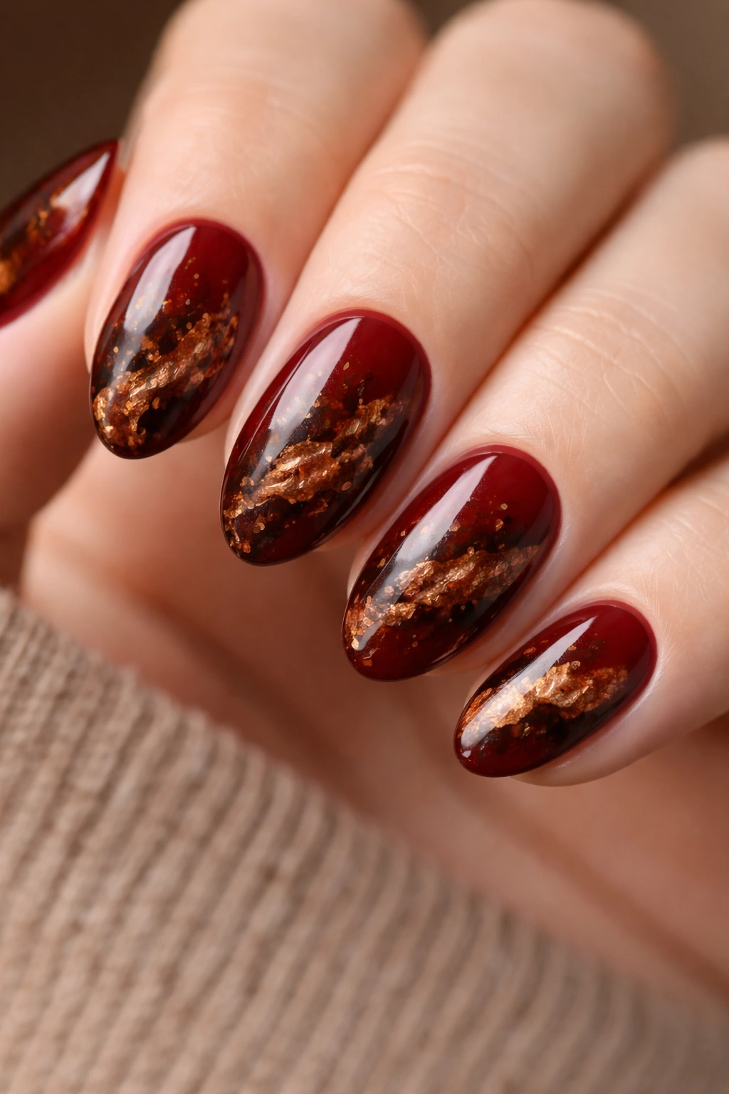 Short almond nails with deep red base and tortoiseshell brown swirls of amber and copper flecks