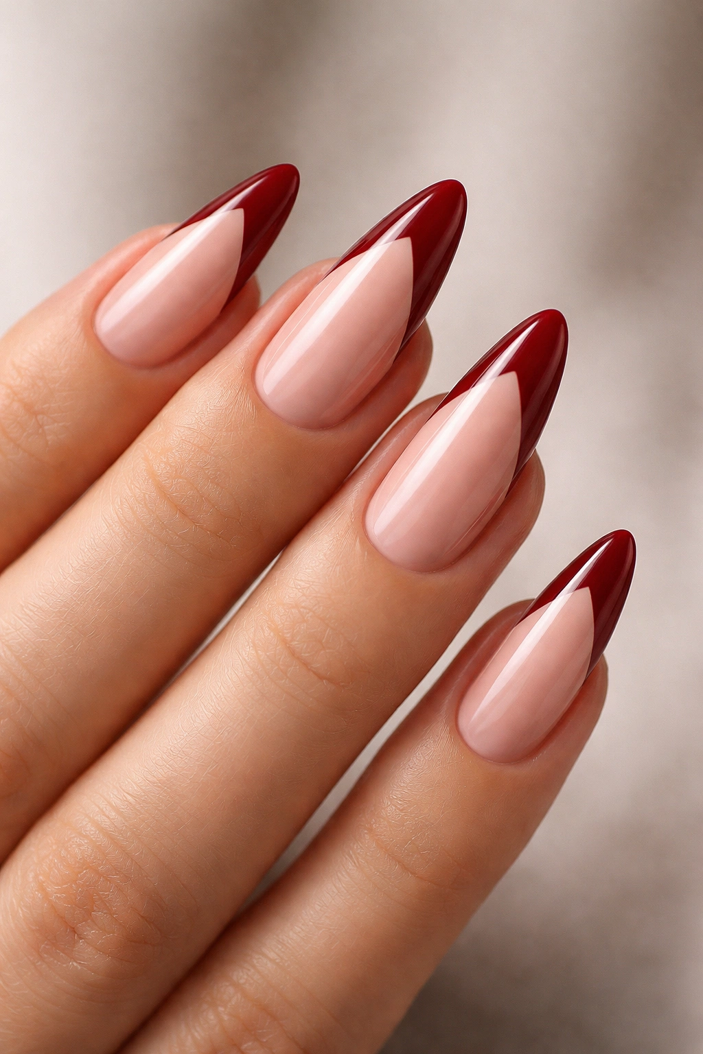 Close-up of almond nails with a V-shaped deep red tip