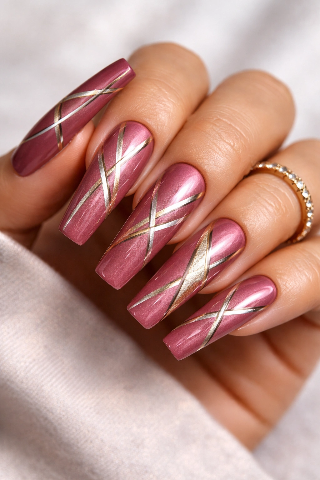 Close-up of deep rose pink coffin nails with metallic geometric patterns on a bare hand