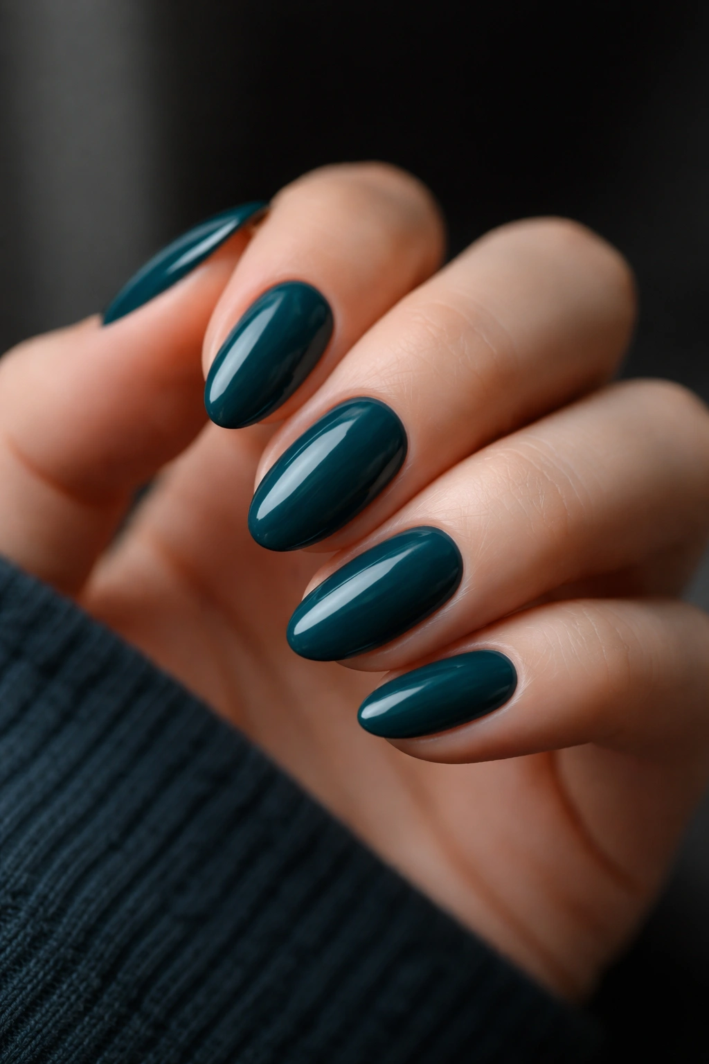 Close-up of deep teal almond nails on a hand