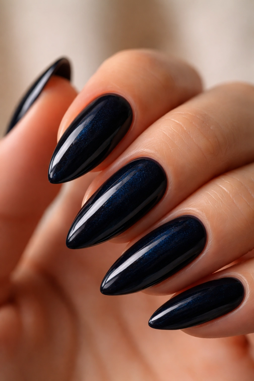 Almond nail painted deep blue-black on bare hand