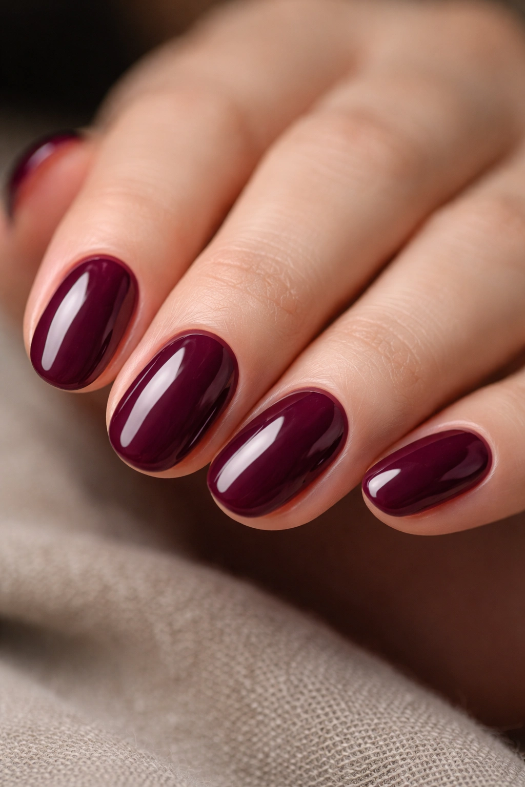 Close-up of deep wine short oval builder gel nails with plum undertone