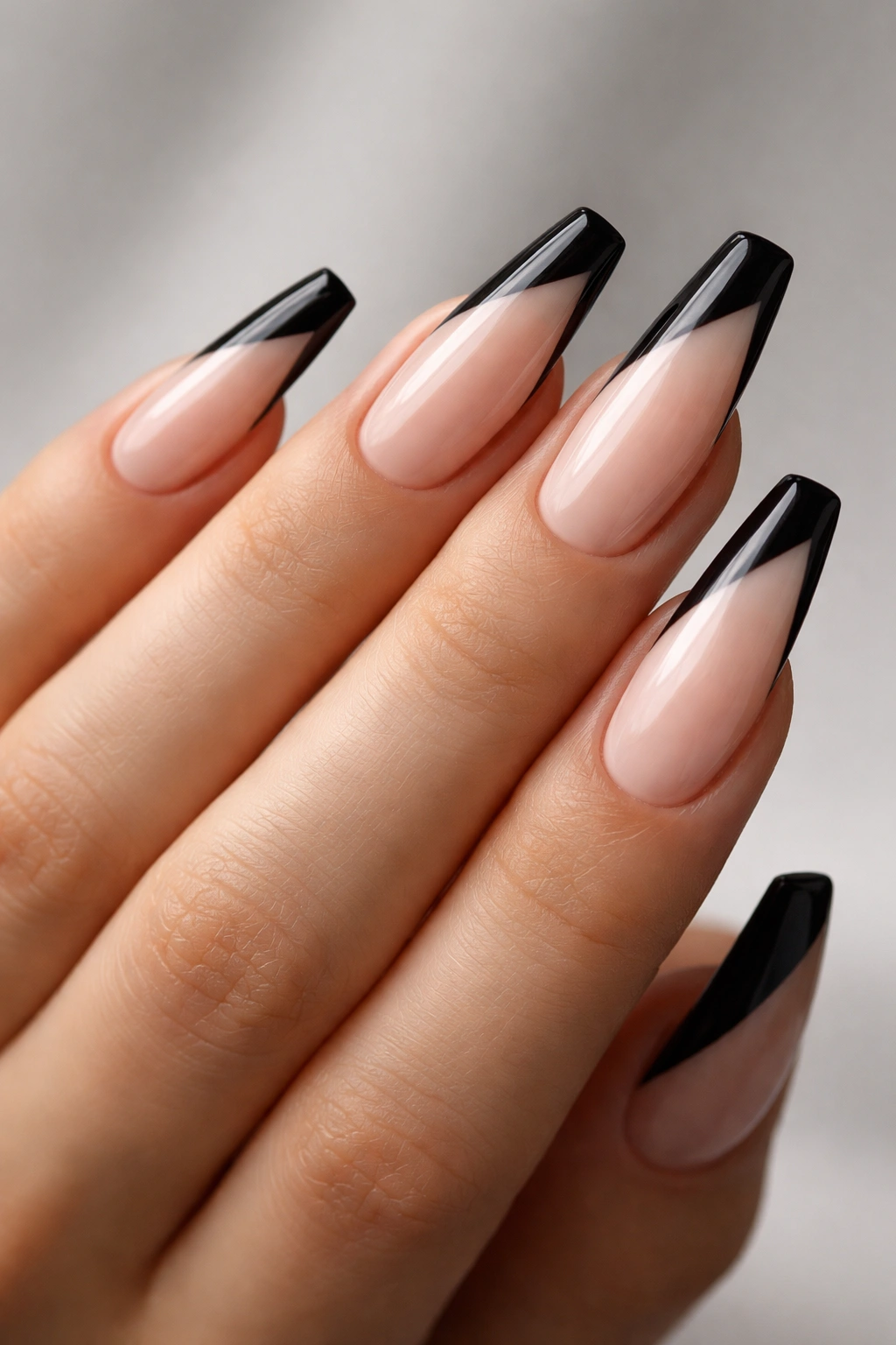 Close-up of diagonal black side-French ballerina nails on a nude base