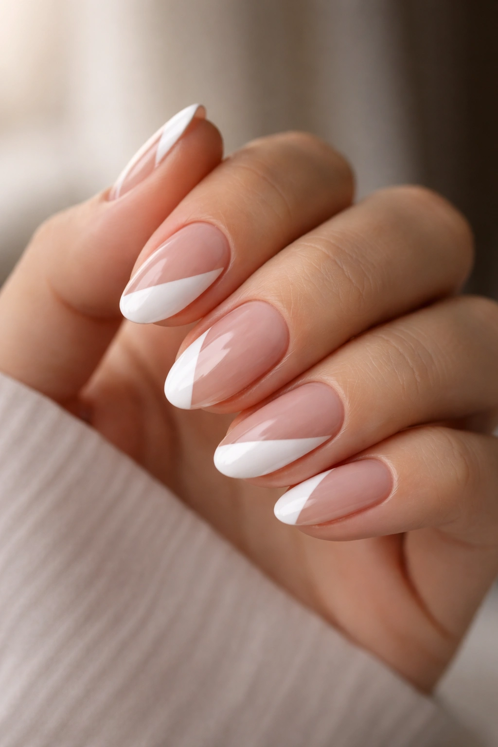 Close-up of short almond nails with a diagonal white tip on alternating fingers